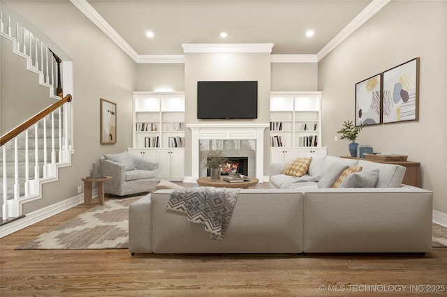 living room featuring a towering ceiling, ornamental molding, a premium fireplace, and hardwood / wood-style floors