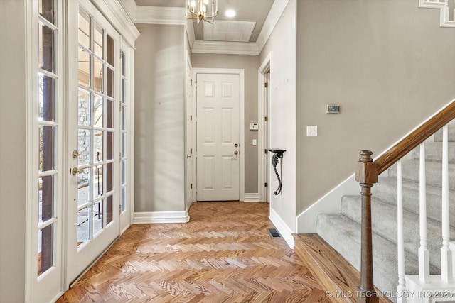 entrance foyer featuring light parquet flooring, ornamental molding, and a chandelier