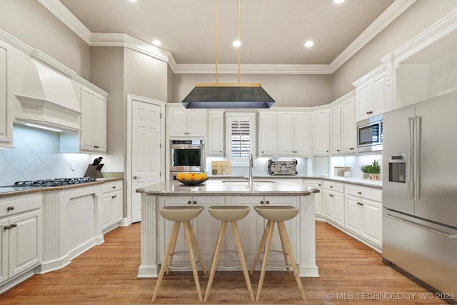 kitchen featuring white cabinetry, sink, stainless steel appliances, and a center island with sink