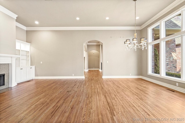 unfurnished living room with an inviting chandelier, light hardwood / wood-style flooring, and ornamental molding