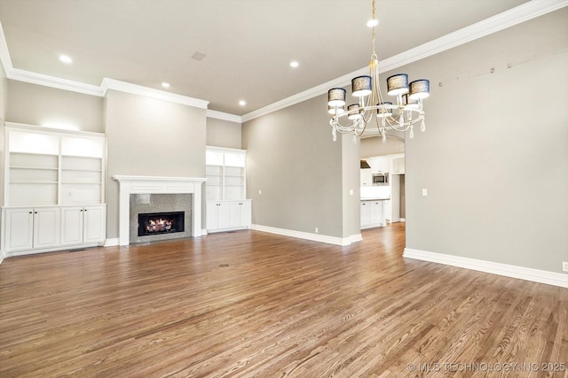 unfurnished living room with an inviting chandelier, ornamental molding, a fireplace, and hardwood / wood-style floors