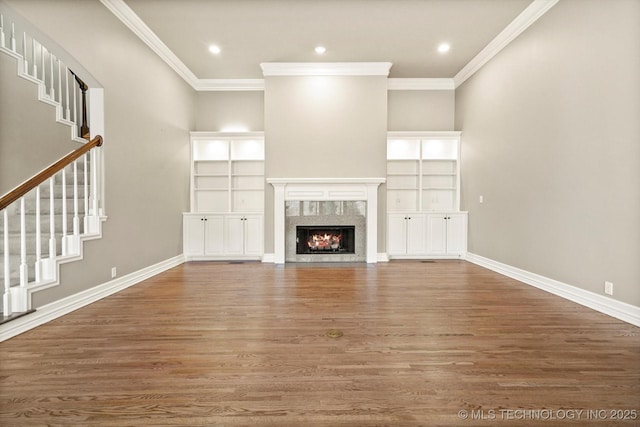 unfurnished living room featuring hardwood / wood-style flooring, a fireplace, and crown molding