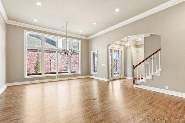 unfurnished living room with wood-type flooring, ornamental molding, and an inviting chandelier