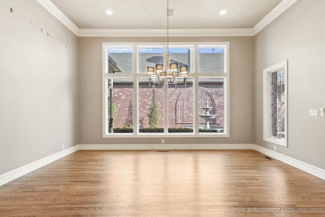 unfurnished dining area with hardwood / wood-style flooring, crown molding, and a chandelier