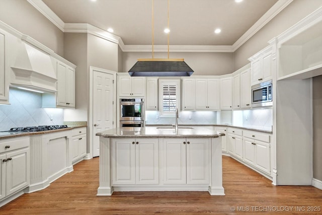 kitchen with white cabinetry, stainless steel appliances, a kitchen island with sink, and sink