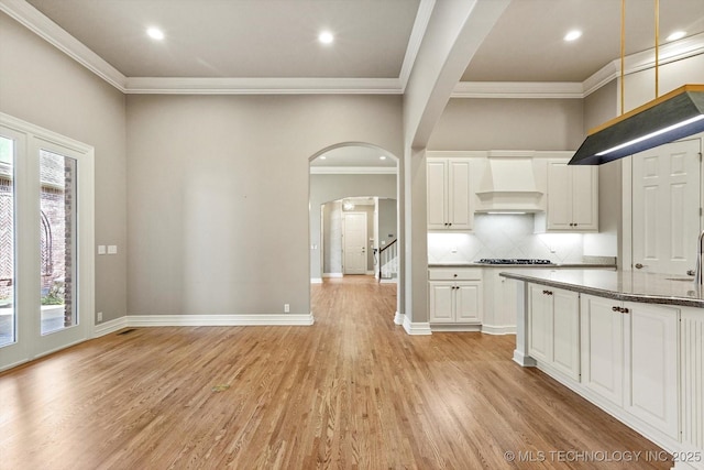 kitchen featuring white cabinetry, crown molding, light hardwood / wood-style flooring, and custom range hood