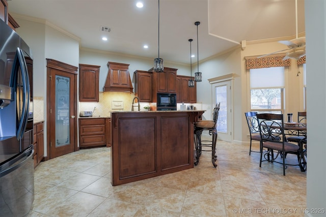 kitchen featuring pendant lighting, a kitchen island with sink, black microwave, fridge with ice dispenser, and decorative backsplash