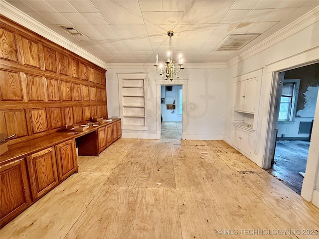 kitchen with pendant lighting, ornamental molding, built in desk, and a notable chandelier