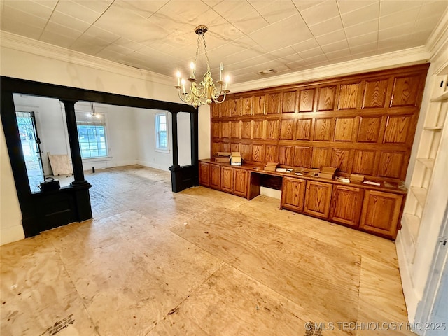 interior space featuring ornate columns, crown molding, built in desk, and decorative light fixtures