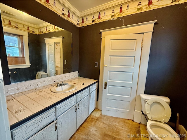 bathroom featuring vanity, hardwood / wood-style floors, ornamental molding, and toilet