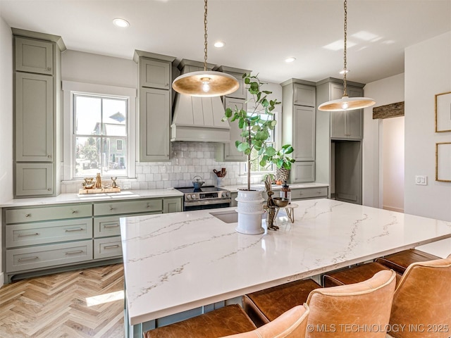 kitchen with pendant lighting, backsplash, light stone counters, a kitchen bar, and light parquet flooring