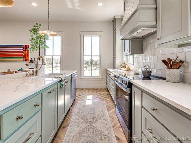 kitchen featuring premium range hood, decorative light fixtures, tasteful backsplash, stainless steel appliances, and light parquet flooring
