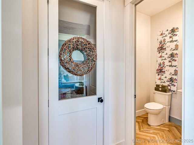 bathroom featuring parquet floors and toilet