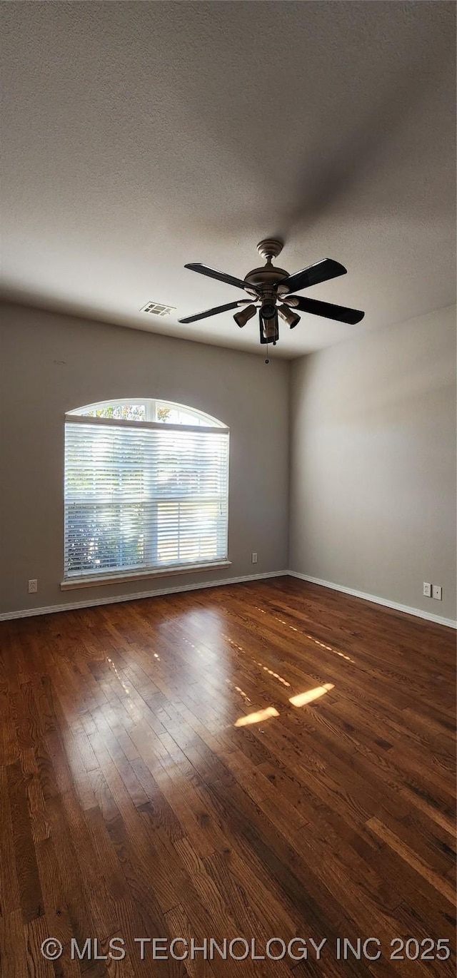 spare room featuring ceiling fan, dark wood-type flooring, and a textured ceiling