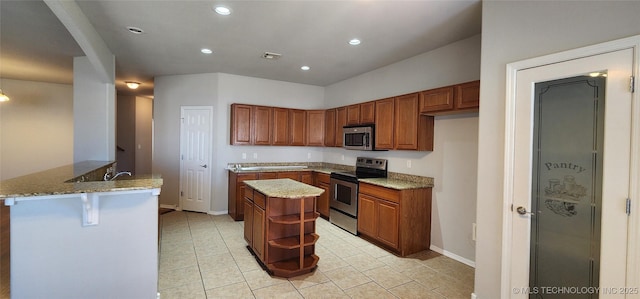 kitchen with light stone counters, a center island, light tile patterned floors, kitchen peninsula, and stainless steel appliances