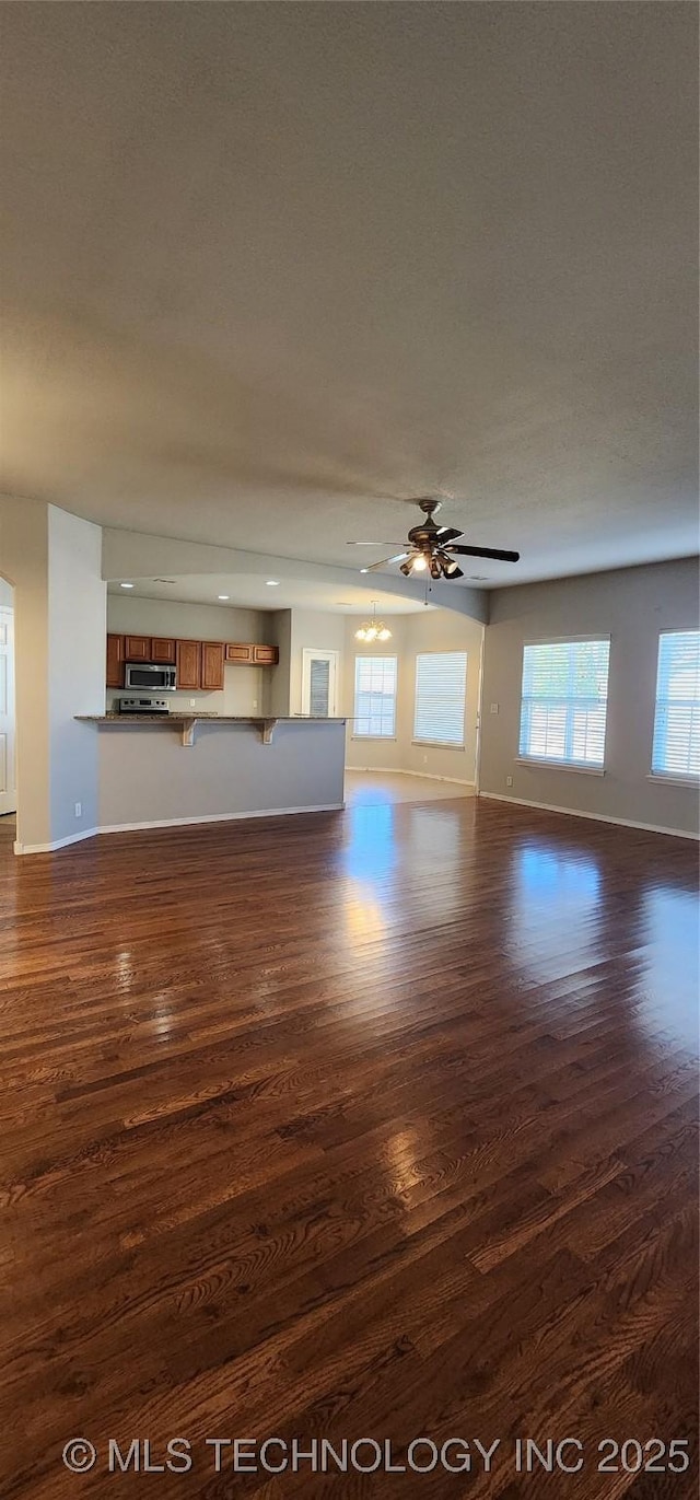 unfurnished living room with ceiling fan and dark hardwood / wood-style flooring