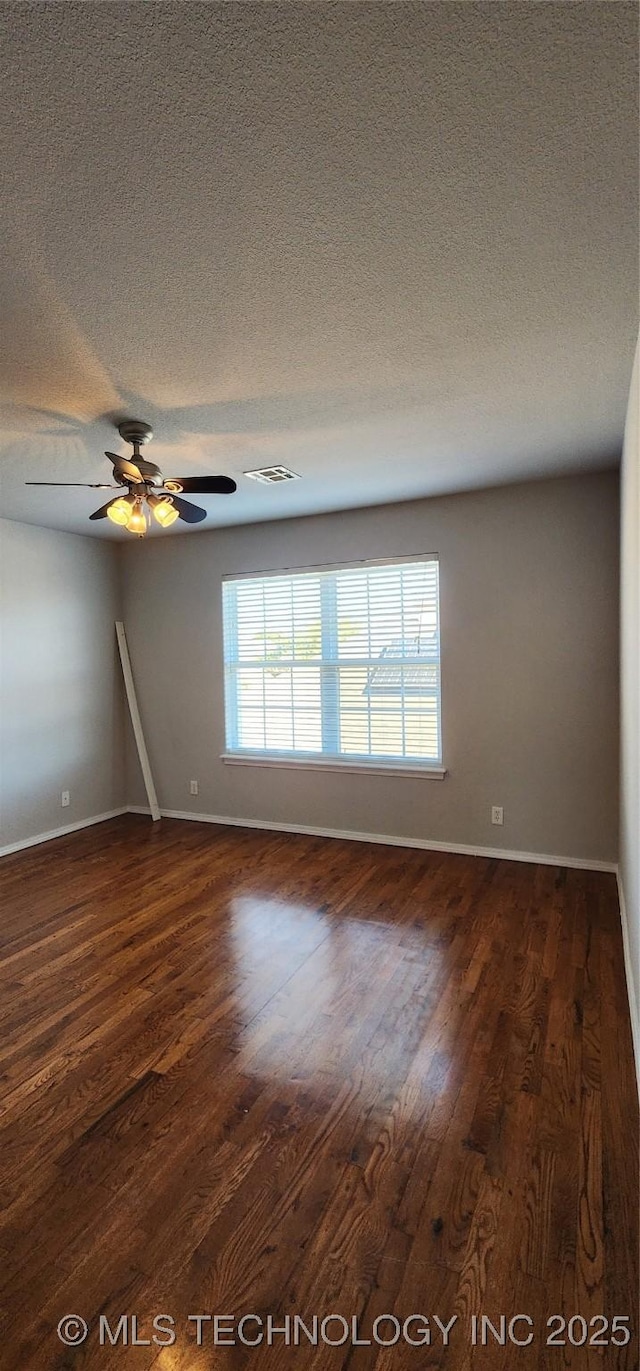 empty room featuring dark hardwood / wood-style flooring, ceiling fan, and a textured ceiling