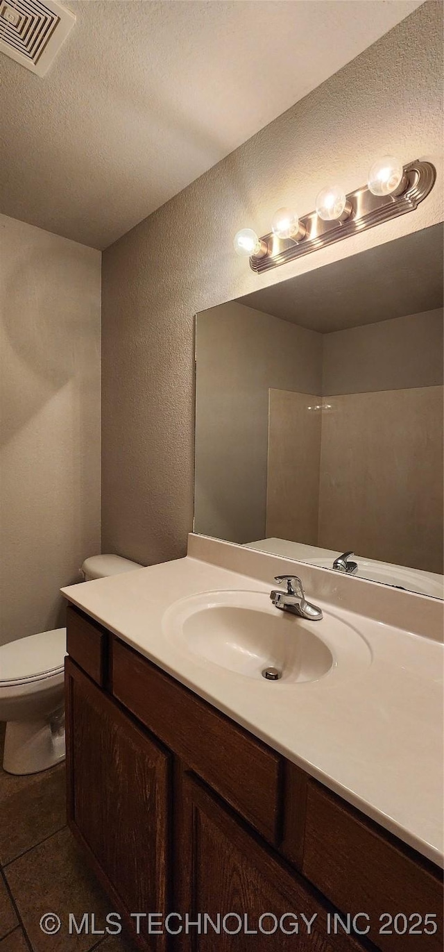 bathroom featuring vanity, tile patterned floors, a textured ceiling, and toilet