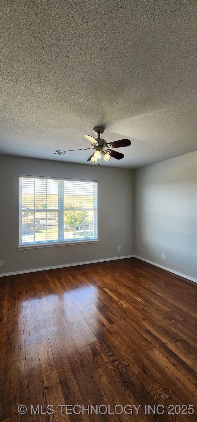 unfurnished room featuring dark hardwood / wood-style flooring, ceiling fan, and a textured ceiling