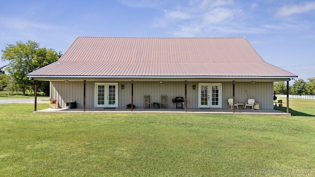 rear view of property featuring french doors, a patio, and a lawn