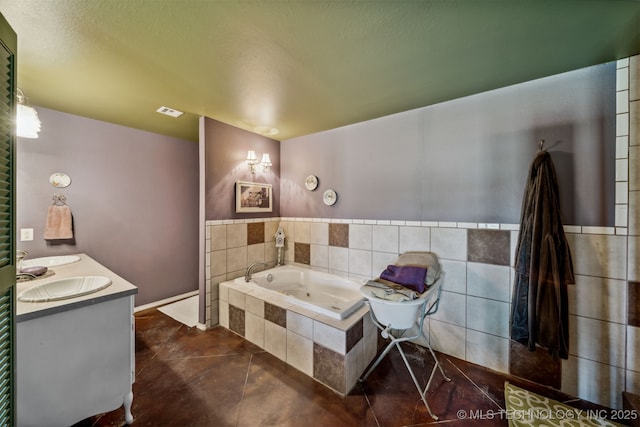 bathroom featuring tile patterned floors, tiled bath, vanity, and tile walls