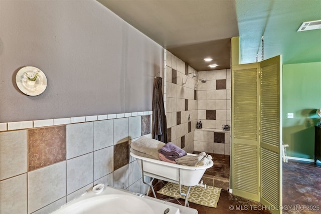 bathroom featuring a bathtub and tile walls