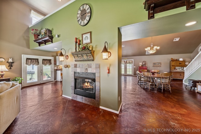 living room featuring a fireplace, french doors, a chandelier, and a high ceiling