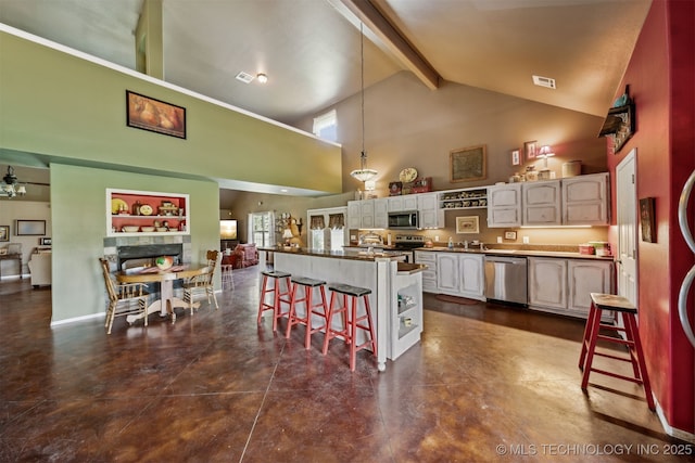 kitchen with beam ceiling, high vaulted ceiling, stainless steel appliances, a wealth of natural light, and a kitchen bar