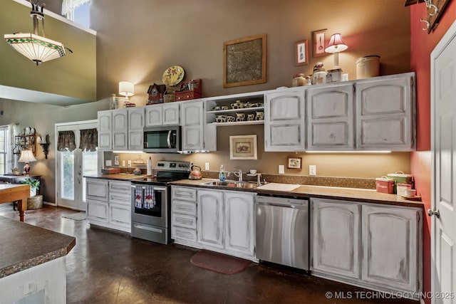 kitchen featuring white cabinetry, a towering ceiling, appliances with stainless steel finishes, and sink