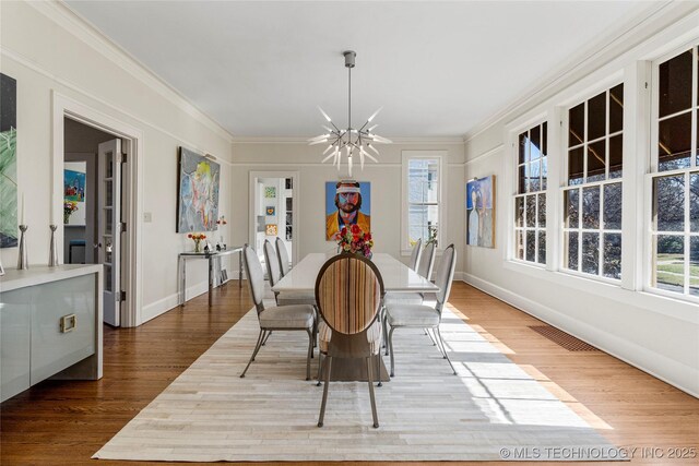 dining room featuring ornamental molding, wood-type flooring, and a notable chandelier