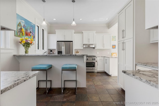 kitchen featuring appliances with stainless steel finishes, a kitchen bar, white cabinets, and light stone counters