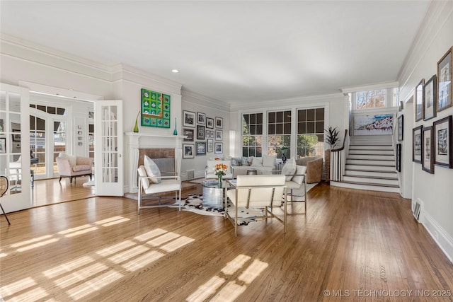 living room with hardwood / wood-style flooring, crown molding, a high end fireplace, and french doors