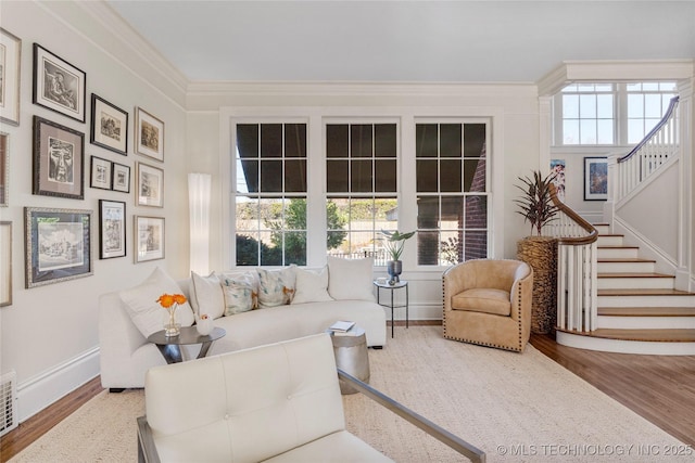 living room featuring a wealth of natural light, ornamental molding, and wood-type flooring