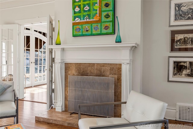 room details featuring a tiled fireplace, hardwood / wood-style floors, and french doors