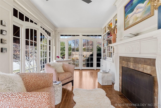 interior space featuring crown molding, dark hardwood / wood-style floors, built in shelves, and a tile fireplace