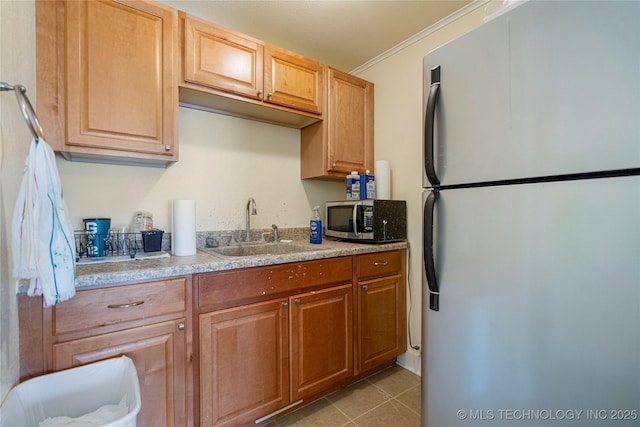 kitchen with light tile patterned flooring, appliances with stainless steel finishes, sink, and ornamental molding