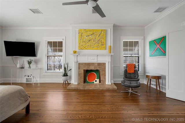 living room with crown molding, dark hardwood / wood-style floors, ceiling fan, and a fireplace