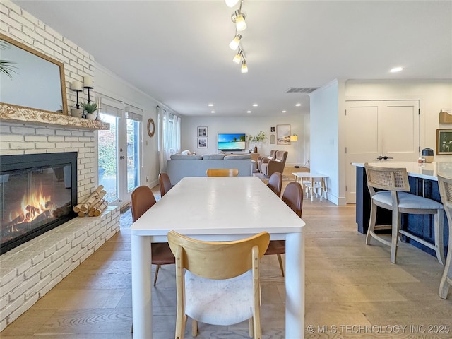 dining area featuring a brick fireplace and light wood-type flooring