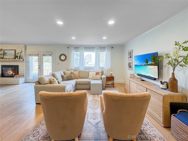 living room with crown molding, a fireplace, and light hardwood / wood-style flooring