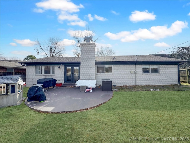 rear view of property featuring french doors, a patio, and a lawn