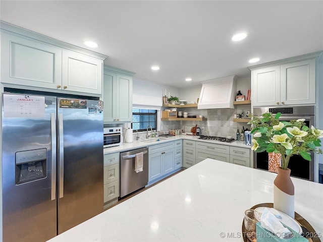 kitchen with sink, decorative backsplash, stainless steel appliances, and premium range hood