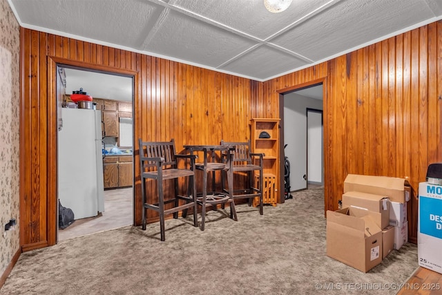 carpeted office with ornamental molding, a textured ceiling, and wood walls