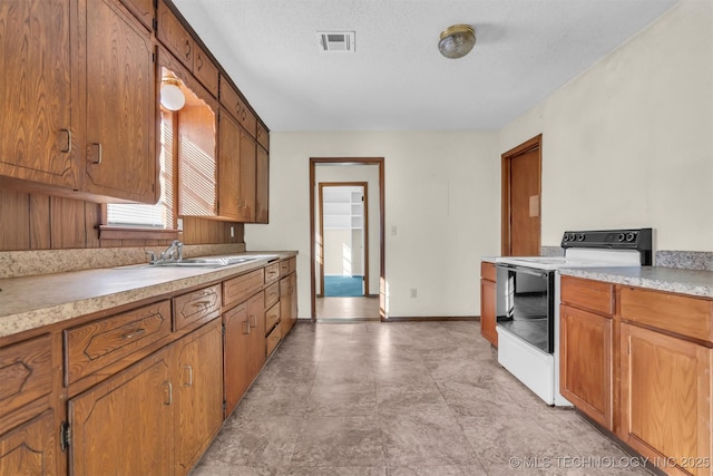 kitchen with white electric range oven, sink, and a textured ceiling