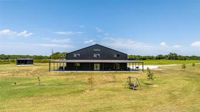 back of property with an outbuilding, a yard, and a rural view