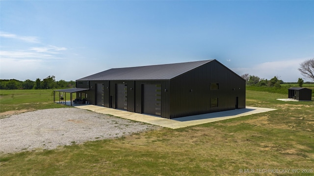 view of outdoor structure with a rural view, a garage, a lawn, and a carport