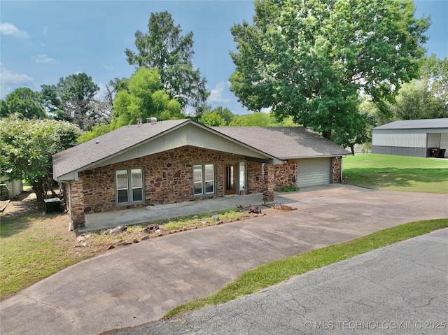 single story home with a garage, a front yard, and central air condition unit