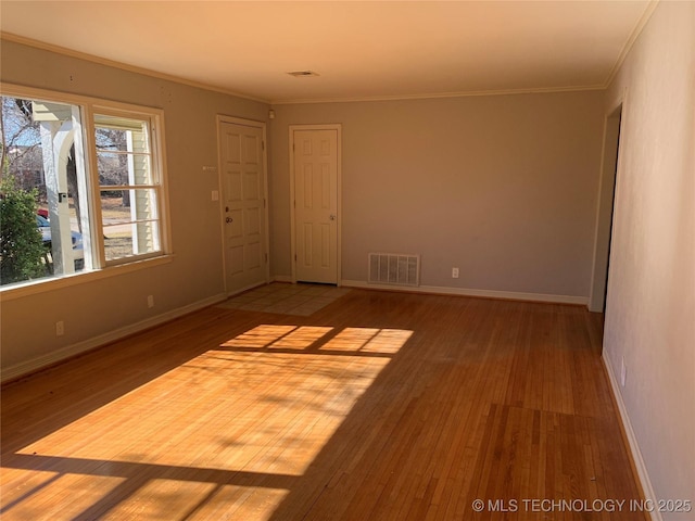 spare room with ornamental molding and light wood-type flooring