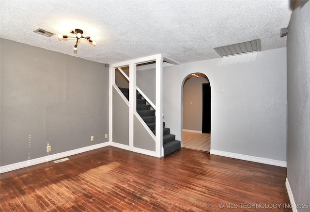 spare room featuring dark wood-type flooring and a textured ceiling