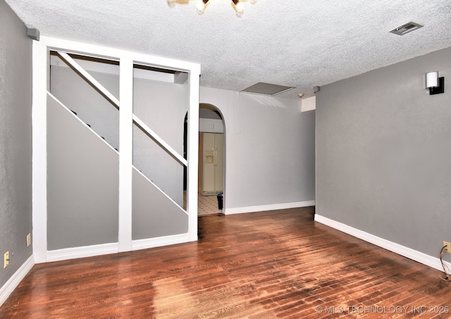6273 E Marshall Pl, Tulsa, OK 74115 - below grade area with wood finished floors, a textured ceiling, arched walkways, baseboards, and visible vents