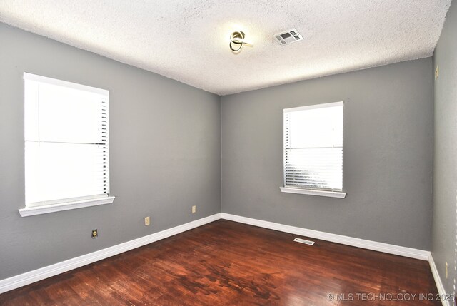 spare room featuring dark hardwood / wood-style flooring and a textured ceiling